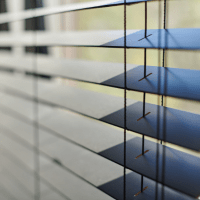 Close-up view of aluminium Venetian blinds in a partially closed position, showing the texture and color.