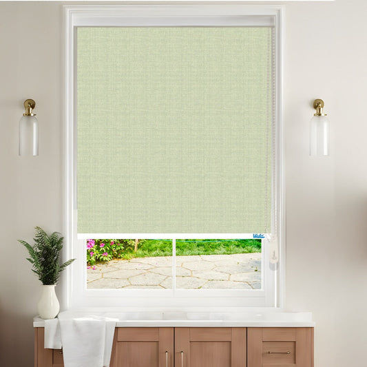 A room with a printed roller blind on the window, in a light color, possibly green, lets in natural light from a visible outdoor area.