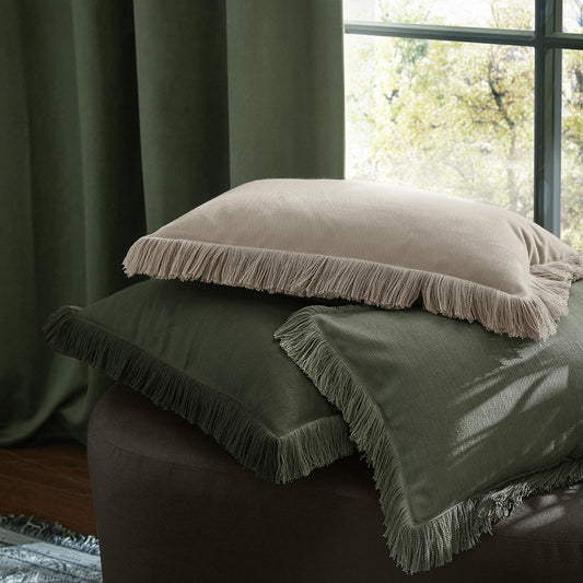 Green cushion with fringe in front of a window